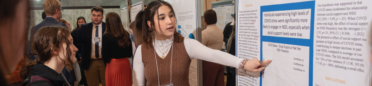 Student presenting research information on a poster